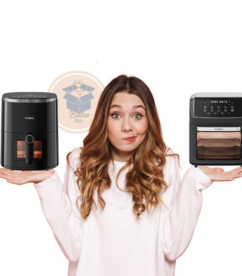 Mulher jovem com expressão de dúvida segurando, uma em cada mão, duas fritadeiras elétricas Gaabor pretas para um comparativo. Na mão esquerda, um modelo de cesto cilíndrico com janela de visualização e painel digital no topo. Na mão direita, um modelo Air Fryer Oven maior com porta de vidro frontal, prateleiras internas e painel touch digital amplo.