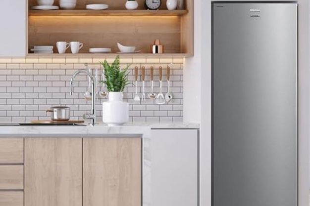 Freezer vertical cinza embutido em marcenaria de cozinha moderna com azulejos brancos e prateleiras de madeira.