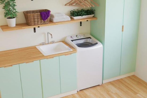 Máquina de lavar branca instalada em lavanderia compacta com armários, pia e prateleiras