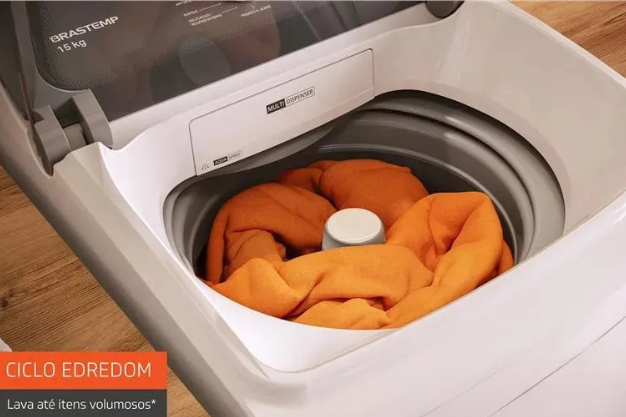 Máquina de lavar com edredom laranja dentro do tambor durante ciclo de lavagem