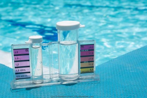 Kit medidor de cloro e pH com tubos de teste ao lado de piscina