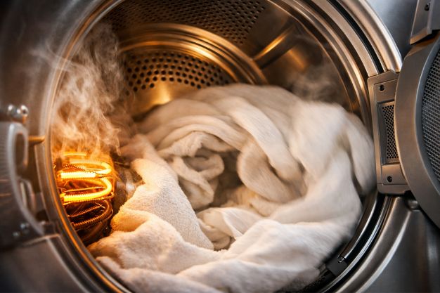 Interior de secadora de roupas com tambor girando, resistência aquecida e vapor durante a secagem