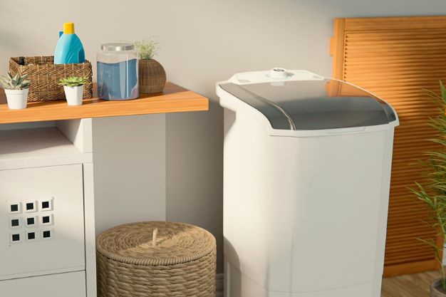Tanquinho de lavar roupas branco posicionado em lavanderia doméstica ao lado de prateleira com produtos de limpeza