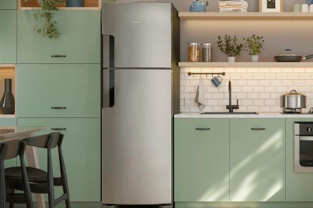 Geladeira duplex inox instalada em cozinha com armários verdes e bancada clara planejada
