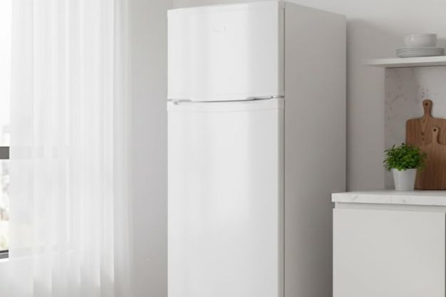 Geladeira branca duplex posicionada em cozinha clara com bancada e objetos decorativos ao lado